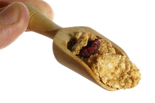 Cereals with dried cherries on small wooden spoon