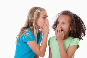 Cute girl whispering a secret to her friend
