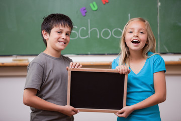 Happy pupils holding a school slate