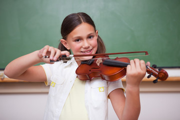 Smiling schoolgirl playing the violin