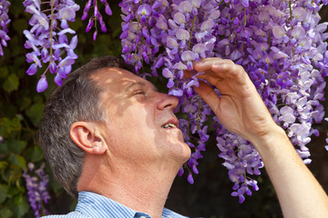 attractive man is smelling park flowers