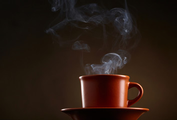 Cup of coffee with smoke over dark background