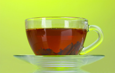Black tea in glass cup on green background