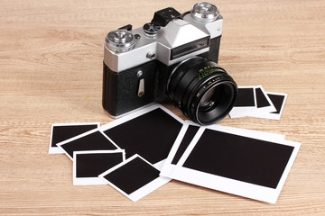 Old photo camera with photo papers  on wooden background