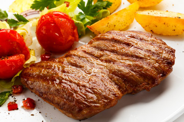 Grilled steak, baked potatoes and vegetable salad