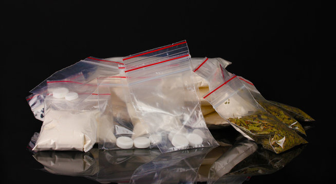 Cocaine and marihuana in packages on black background
