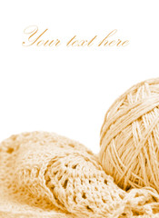 Beige knitted garment andball of thread isolated on white