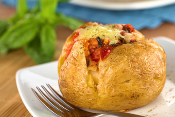 Baked potato with tomato filling and cheese on top