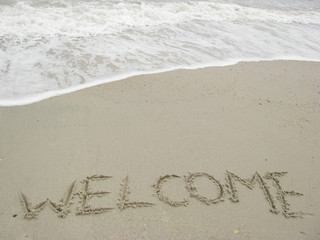 welcome written in a sandy tropical beach