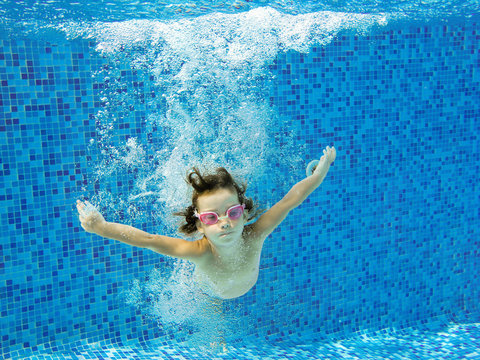 Child in swimming pool, underwater. Kids sport