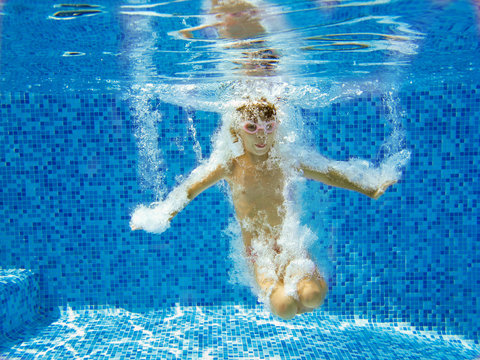 Happy child jumps to swimming pool, underwater