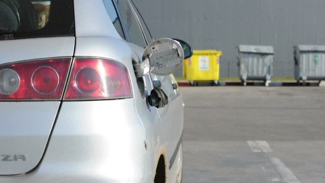Man stands at the gas station and fueled his silver car