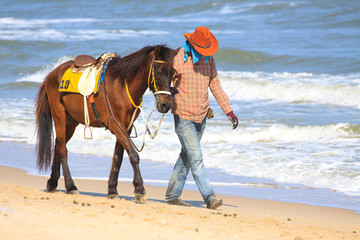 cowboy walking with his horse on the sea beach