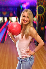 Fototapeta na wymiar beautiful girl stands and keeps in hand ball in bowling club