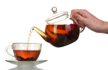 Glass teapot pouring black tea into cup isolated on white