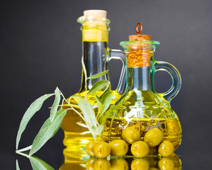 olive oil in jars and olives on gray background