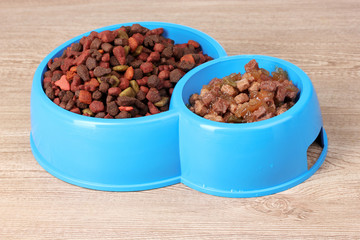 Dry cat food in bowls on wooden background