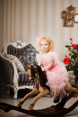 Child in a pink dress on a toy horse