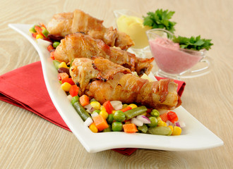 roast chicken leg wrapped in bacon with vegetables