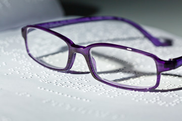 Brille und Buch in Blindenschrift. Braille