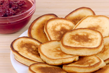 heap of pancakes with bowl of strawberry jam