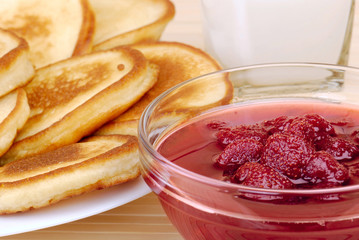 heap of pancakes with bowl of strawberry jam