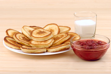 heap of pancakes with bowl of strawberry jam