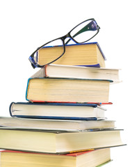 glasses at a pile of books on white background close-up