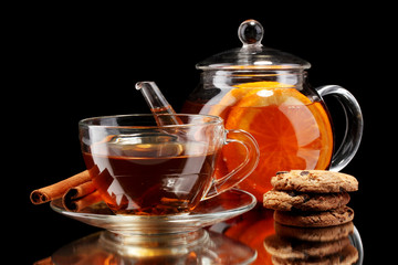 Glass teapot and cup with black fruit tea and cookies isolated