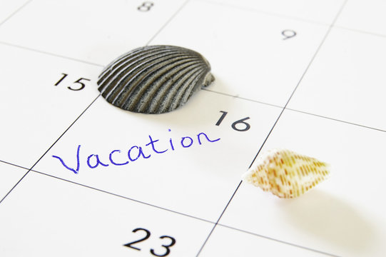 closeup of a celendar with "vacation" text and seashells