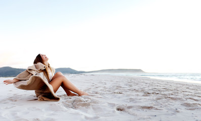 Fototapeta na wymiar Young woman sitting on the sand