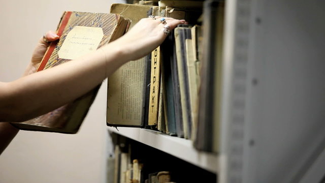 woman considering a book in the library