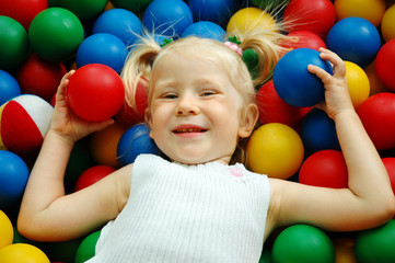 Fototapeta na wymiar The little girl lies on color balls