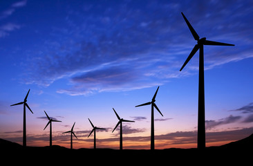 Silhouette of windmills on sunset background with space
