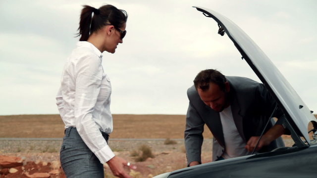 Business couple having fight by the broken car