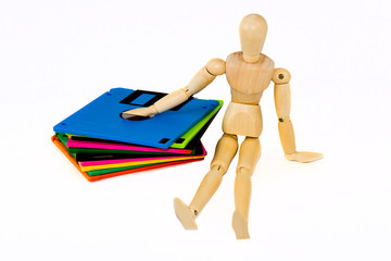 wooden manikin sitting near diskettes isolated 