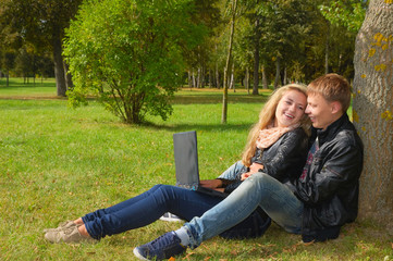 teenage couple studying with a laptop in the park