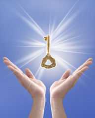 the key to success (hand holding key against blue sky)