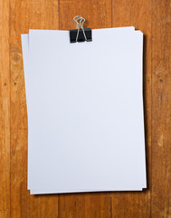 Black clip and White blank note paper hang on wood pane