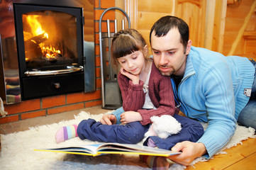Father and daughter reading in front of fireplace