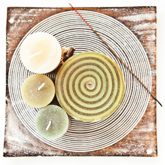 Decorative candles and incense stick on the tray on the white ta