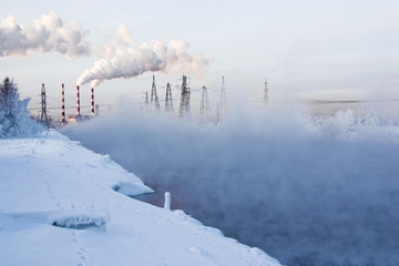 Winter landscape with steam over the river and factory