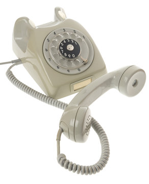 An old gray vintage rotary style telephone with the handset off