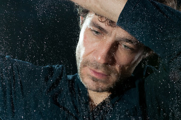 Trauriger Mann hinter nasser Fensterscheibe