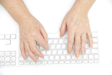 Hands of an old female typing on the keyboard