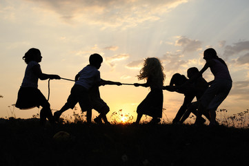 Fototapeta na wymiar Silhouette, group of happy children playing on meadow