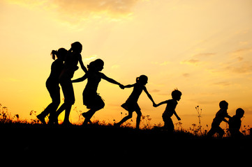 Silhouette, group of happy children playing on meadow