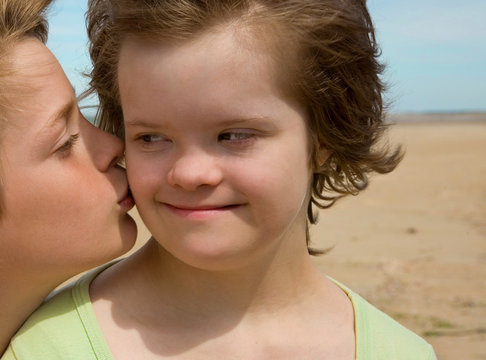 A boy kissing her sister with Down syndrome.
