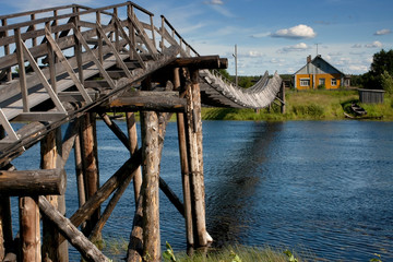 Fototapeta na wymiar Vintage wooden bridge across the river in North Russia