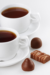 Cup of tea with sweets on white background